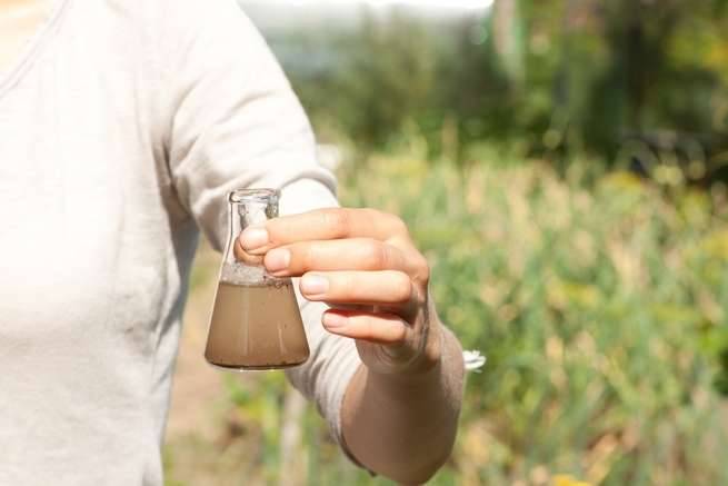 Woman holding glass vial of dirty water